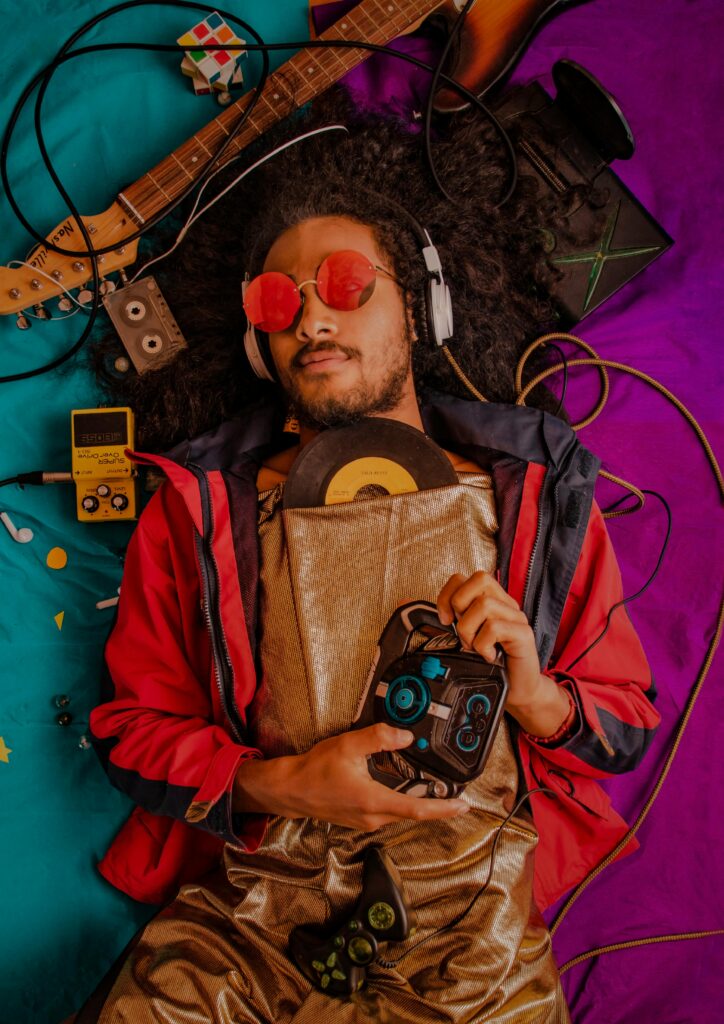 Man with afro and headphones enjoying retro music surrounded by vintage items.